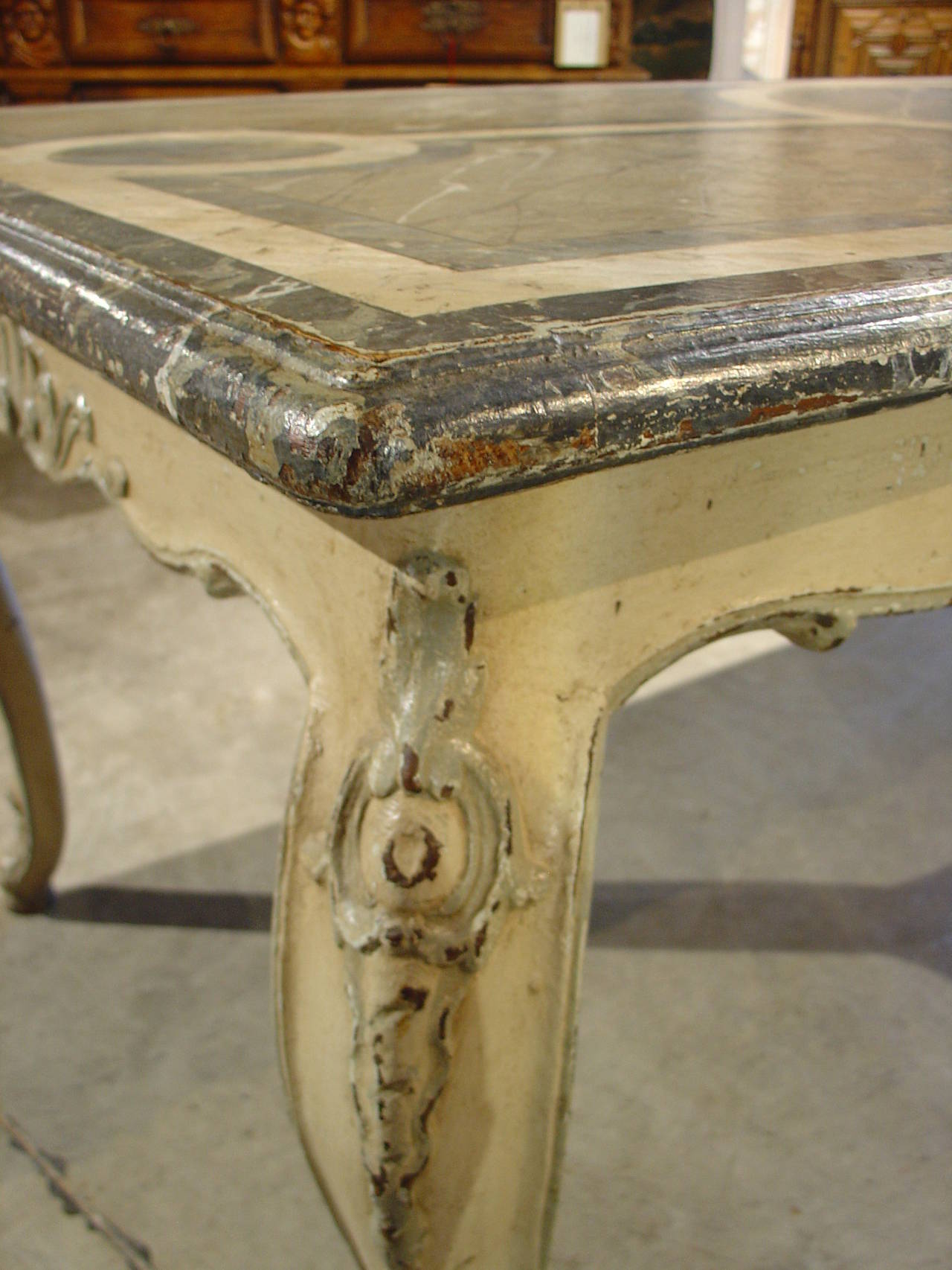 This antique, French painted rectangular dining table is in the Louis XV style and is reminiscent of Provence. It has a painted faux marble top in tones of pale green, medium green and dark green with beige veining running throughout. The design on