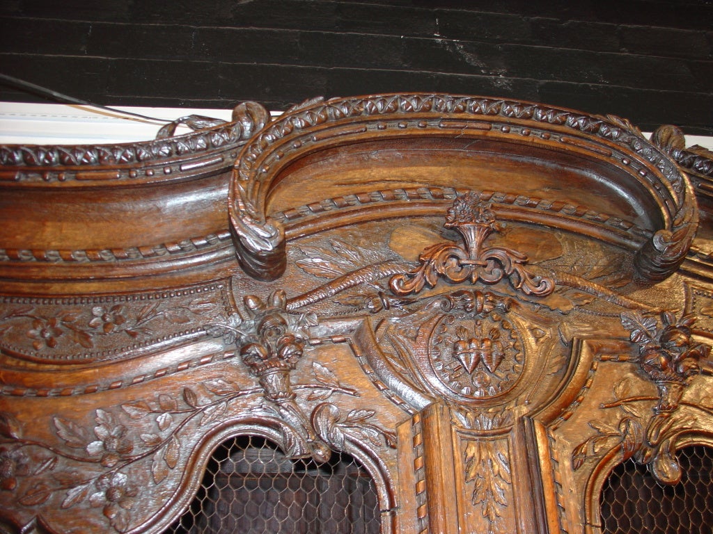 This antique French, European oak, wedding armoire has superb, finely carved details of ornamentation in the Transitional Style.  Armoires from Normandy often shared traits from both Louis XV and Louis XVI. Oak, being a hardwood, is particularly
