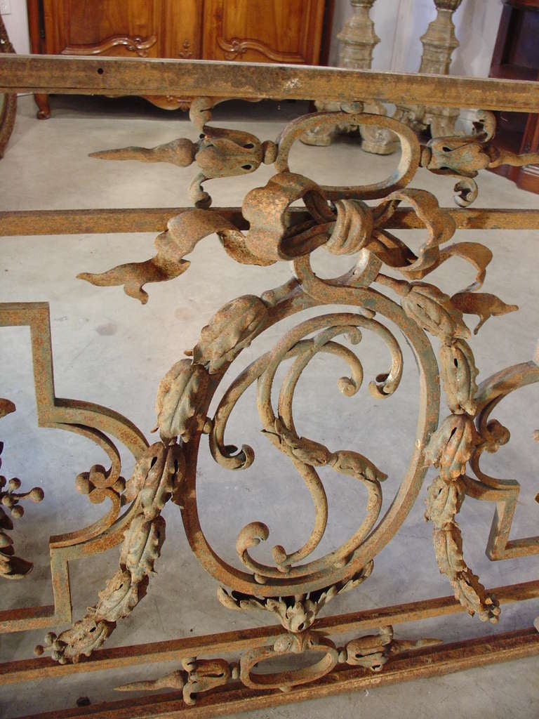 This is a magnificent antique French balcony gate with highly unusual hand forged motifs.  For instance, imagine forming the double knotted crinkled bow, particularly the double knot.  This was not an easy task to do with tongs and a hot fire.  The
