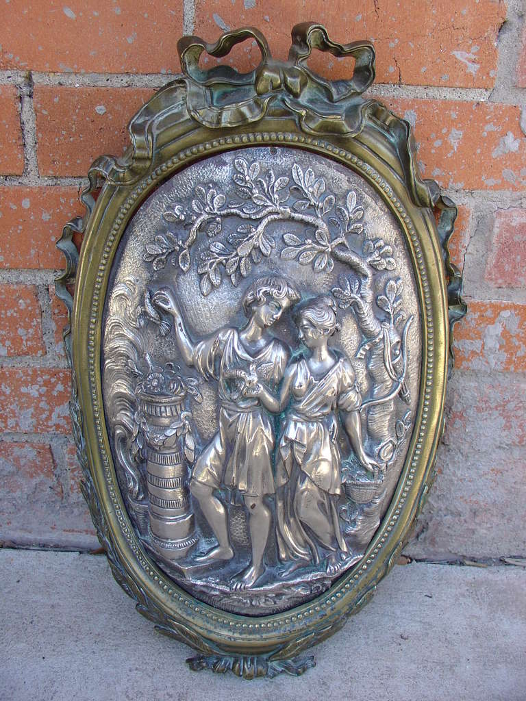 Full bronze

This charming antique French silvered bronze medallion has a scene depicting a young man and woman picking fruit from the trees. The bronze frame has crinkled beribboned bows and leaves falling halfway down each side and meeting up