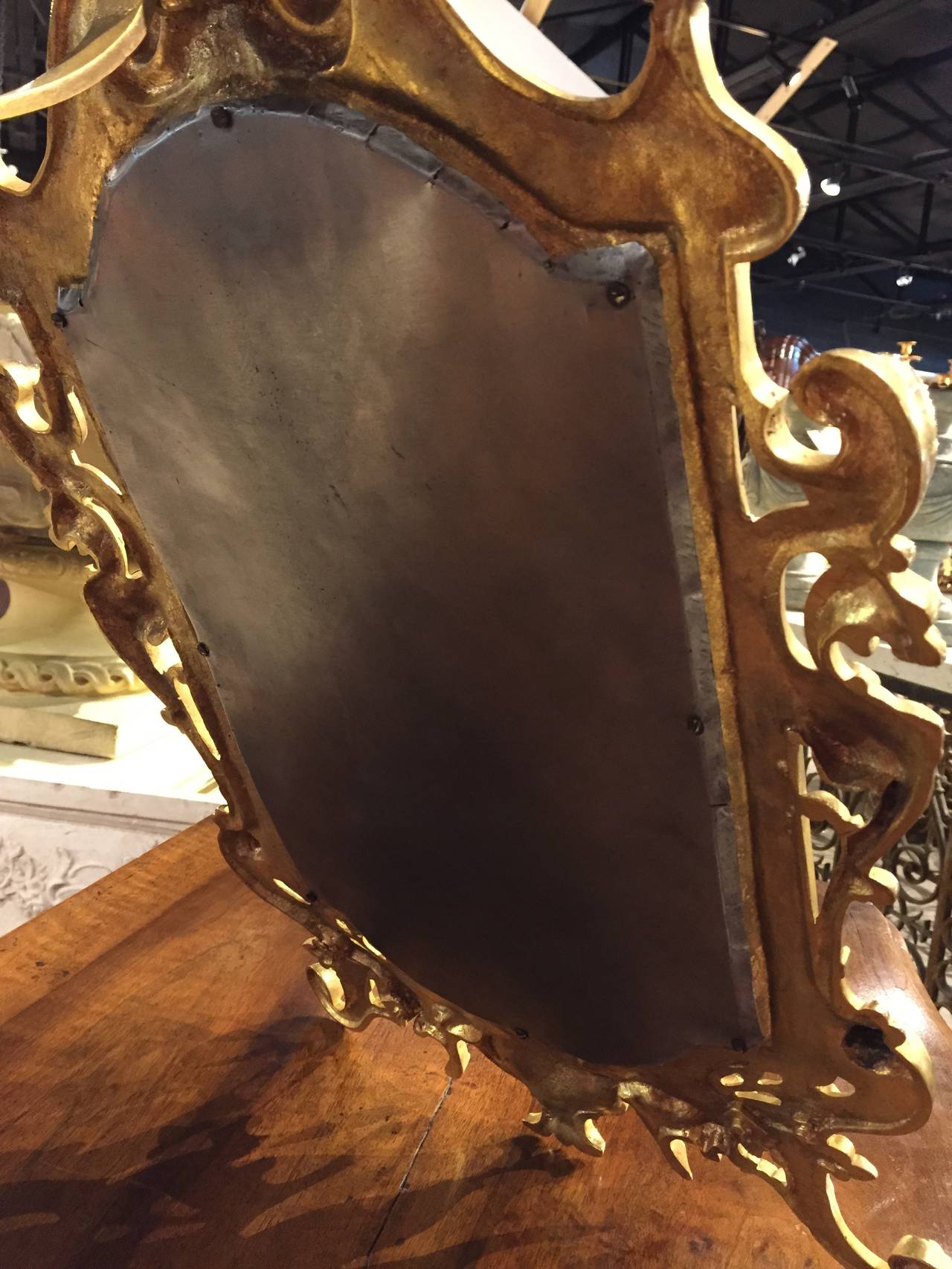 This beautiful bronze table mirror exhibits very refined, chased motifs and dates to the mid 1800s. The interior shape that houses the beveled glass is arched with right angles at the top and bottom. The bronze surrounding this has a myriad of
