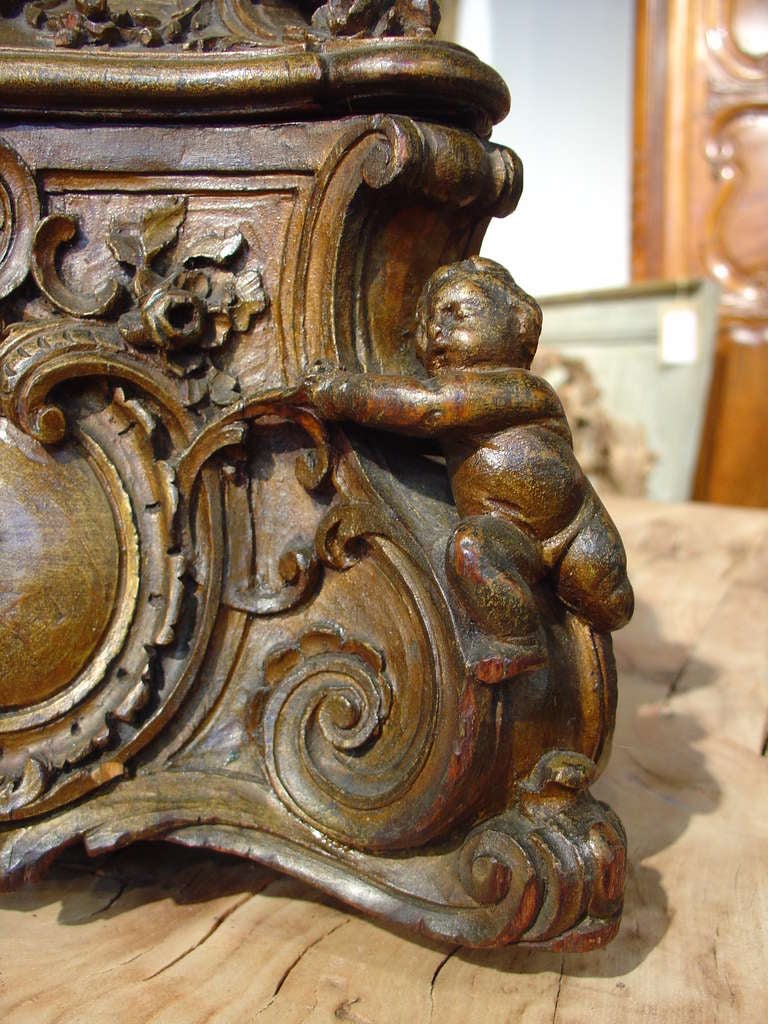 This antique Italian tabletop box has been very finely hand carved out of fruitwood and has a gilded glaze similar to Vernis Martin.  It has a hinged top with cherub finial surrounded by draping, a qiver with arrows and a shell on a conforming case.