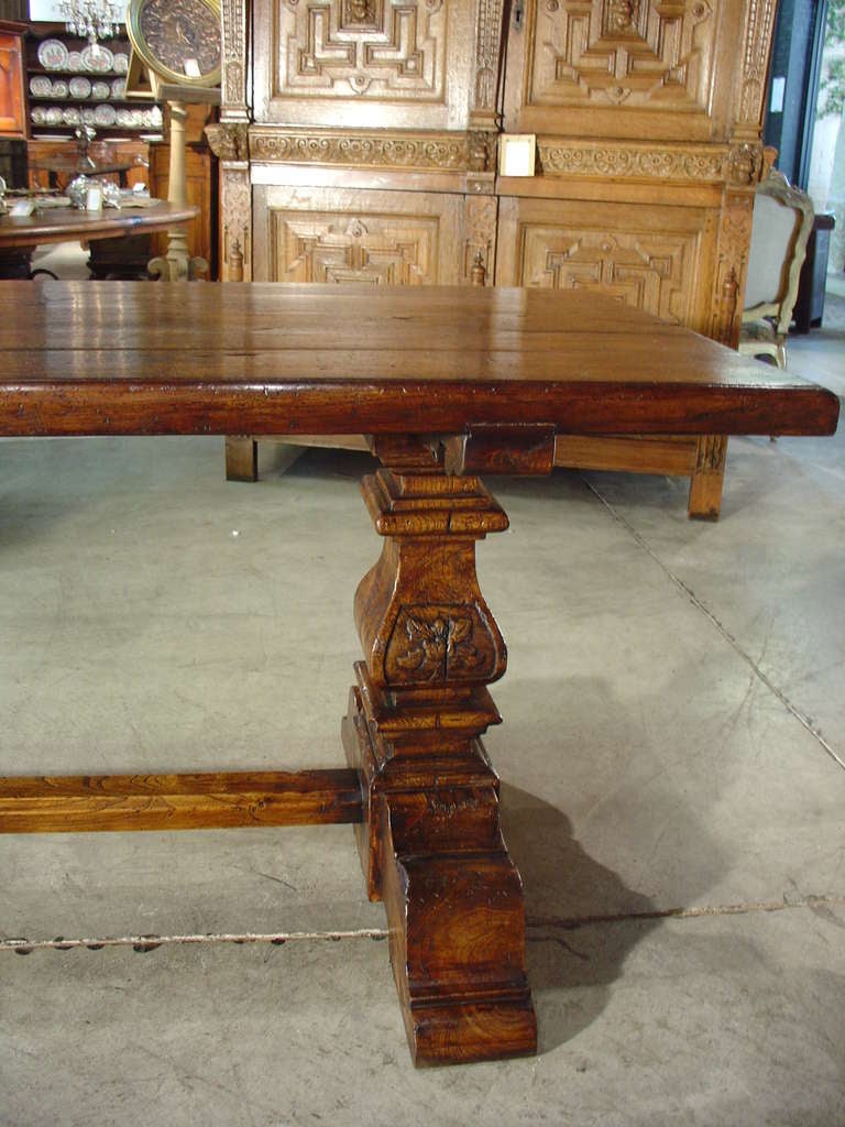 This beautiful Italian Renaissance style oak table was constructed in the 1900s.  It features two balusters with foliate motifs at either end of the table and rests up platform feet.  There is a central beveled stretcher or trestle running between