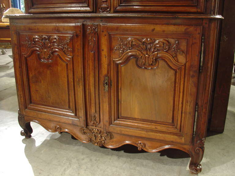 This magnificent 18th century fruitwood armoire from France has a beautiful burled wooden panels and a stunning patina.  The unusual hand carved motifs are subtly different from door panel to door panel, featuring wild flowers, garden flowers,