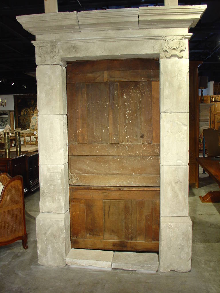 This stunning and elegant French limestone door surround will be an attribute to any front door.  It has a stepped out cornice presiding over a frame of rectangular blocks of limestone on plinths.  There is a motif atop each side of the frame of a
