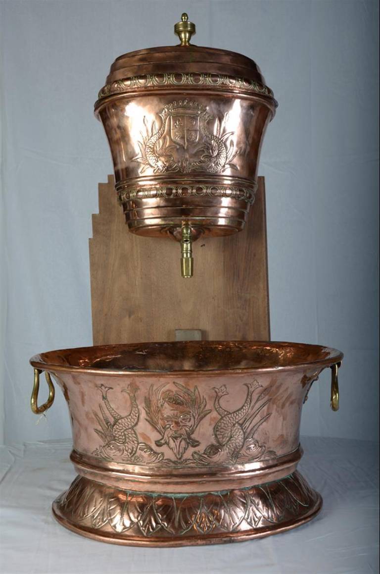 This beautiful highly worked French repousse copper lavabo has motifs of a coat of arms with a crown and twin dolphin supporters to either side. The upper piece was a tank for holding water, and the lower portion is the basin, so this was