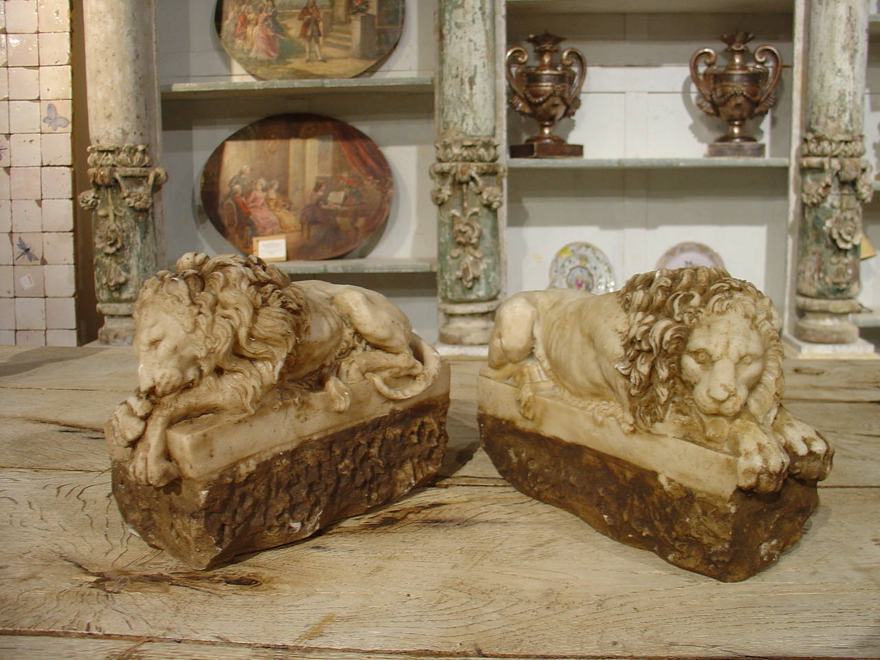 This fabulous pair of small hand carved Italian marble lions depicts two lions resting on their stomachs.   They are on rectangular plinths atop a chiseled rough base.  One lion has crossed paws, taking a nap, while the other lion has his head