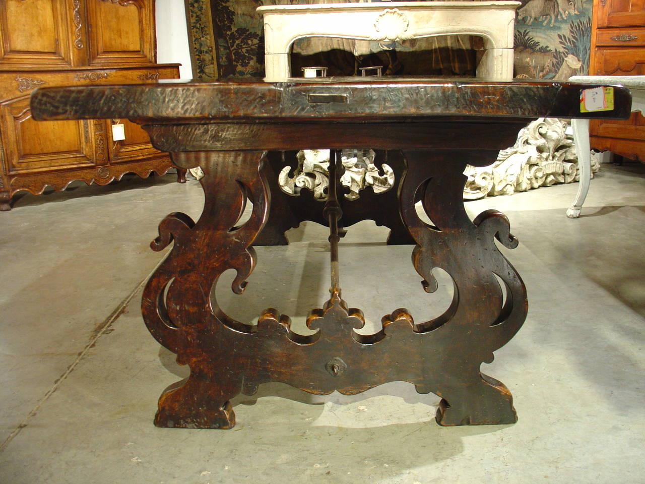 From Tuscany Italy, comes this majestic walnut wood table with hand forged iron shaped stretcher and lyre shaped legs.  The legs are pierced, delineating the outer edges of a stylized bird.  It dates to the first half of the 1800’s and has a deep