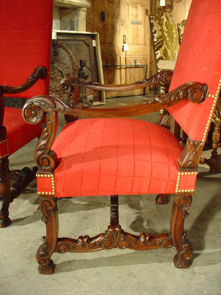 These beautifully hand carved antique French walnut wood fauteuils or armchairs are in the Louis XIV style .  They have H-shaped stretchers with the sides having full hand carved motifs of central palmettes ending in c-scrolls. The central cross