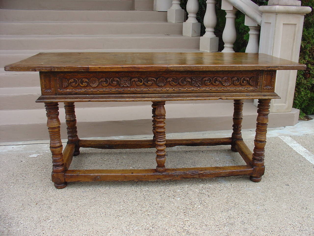 This rare and exceptional Spanish walnut wood center table/console has a single plank rectangular top with an overhang.  Beneath it is a decorated frieze on all four sides indicating it was intended to stand in the center of the room.  This was a