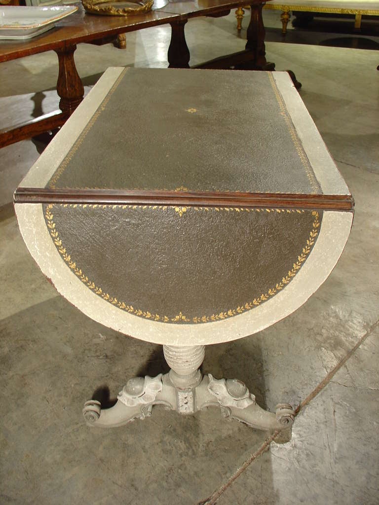 This elegant antique, painted French bureau or desk has a most unusual painted top surface. The leather desk mat is really just a trompe l’oeil painting of a real leather desk mat, complete with surround of gilded motifs. This two drawer desk with