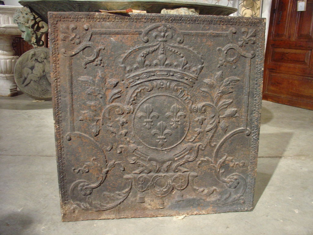 This beautiful, large fireback is from Dijon, France in the early 1800s.  This antique French fireback is from Dijon and has raised ornamentation of a Royal Coat of Arms.  There is the Crown atop a field of triple fleur-de-lys flanked by scrolling