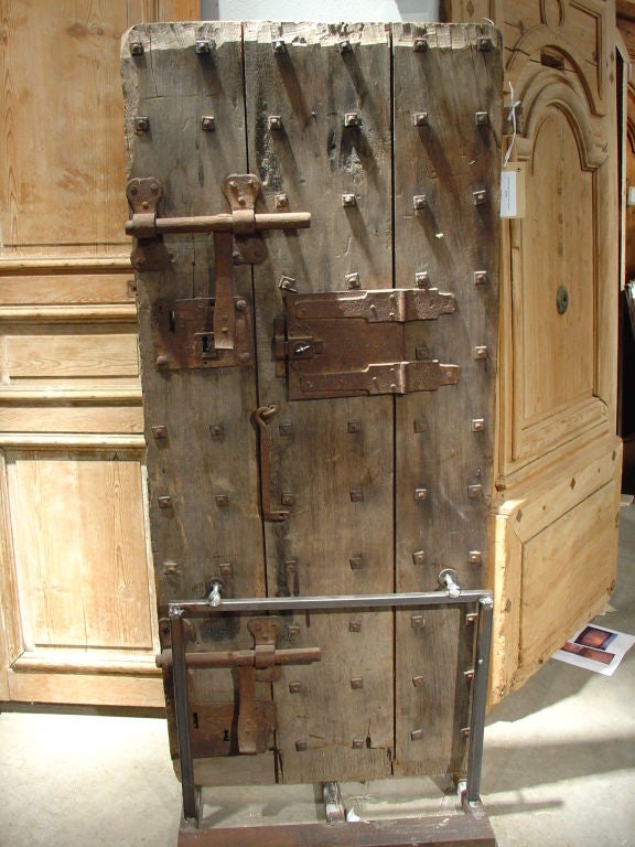 This is an actual antique jail door from 18th century France! It is quite short at just 64 inches tall, but it is adorned with heavy iron locking devices and a small center iron panel. The panel opens and closes, and was probably used to pass food