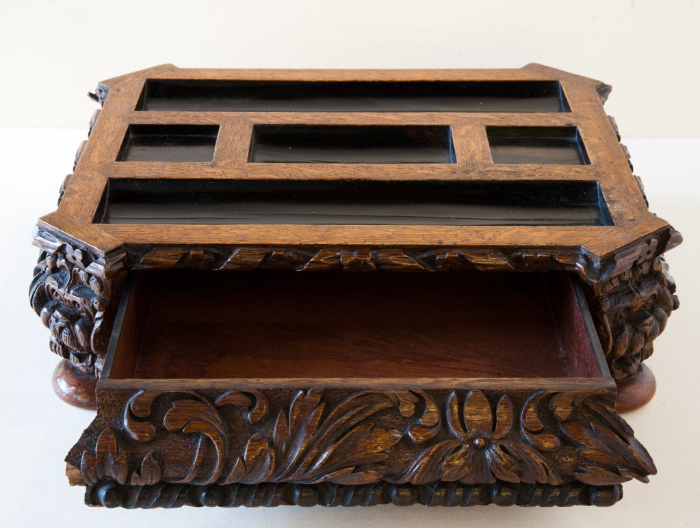 Victorian oak and ebony partners desk ink stand with carved foliate decoration and carved lion likeness on each of the four corners. With opening center drawer and supported on four bun feet.