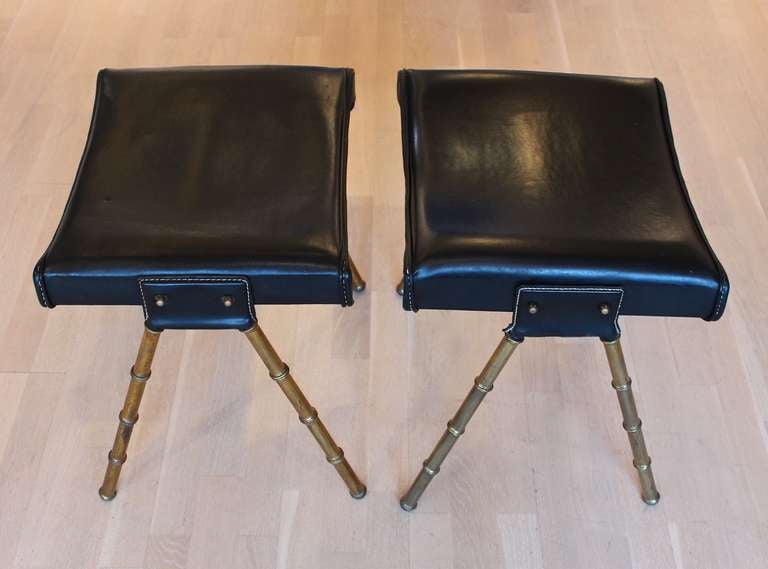 Pair of stools with stitched skai seats and faux bamboo brass legs by Jacques Adnet.
