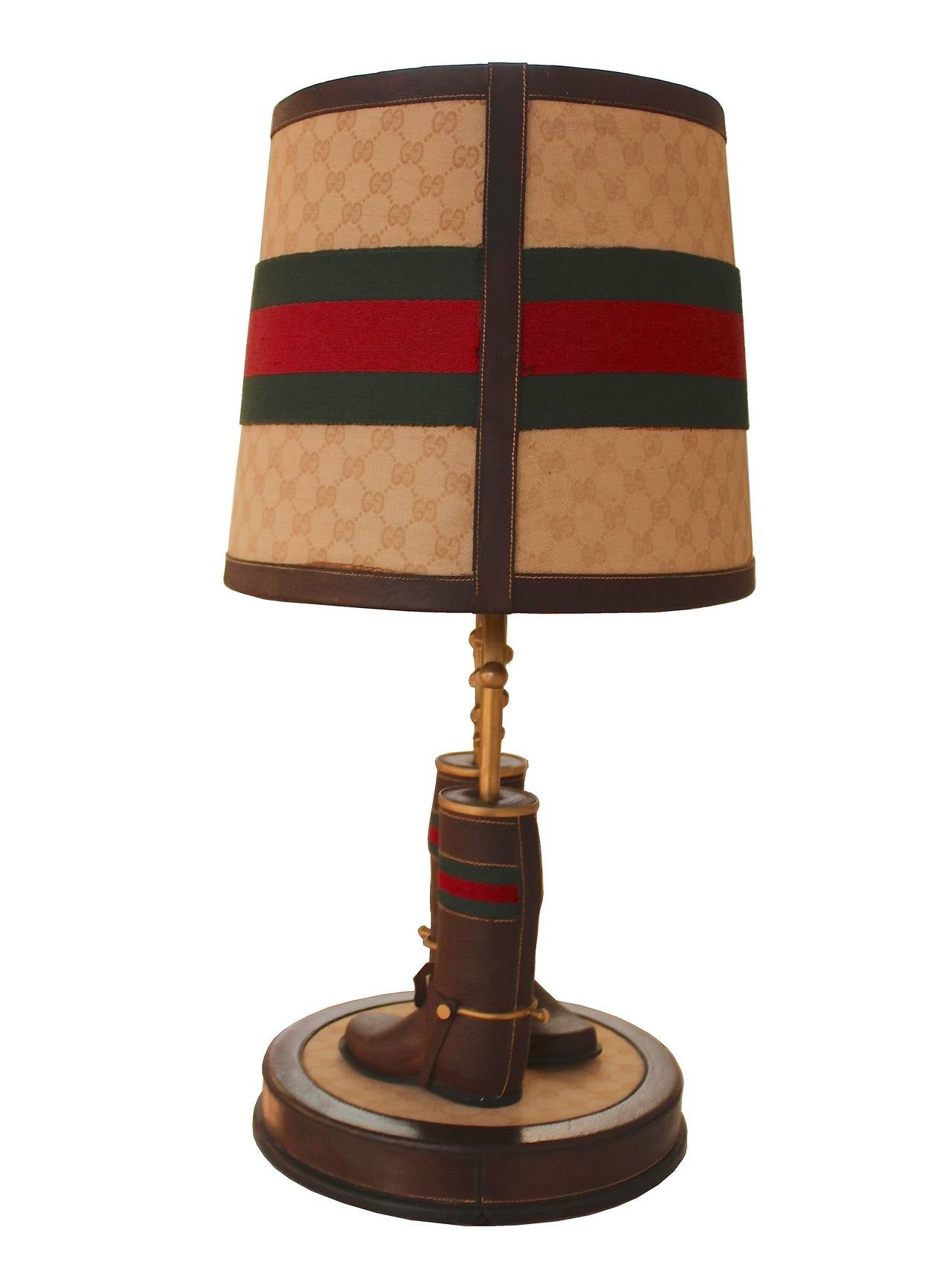 Rare table lamp by Gucci with horseshoe and boots with stirrups.
Gilt metal, leather, webbing and Gucci monogrammed fabric. These lamps were possibly not for retail but part of the display in the Gucci boutiques.
There is one in the collection of