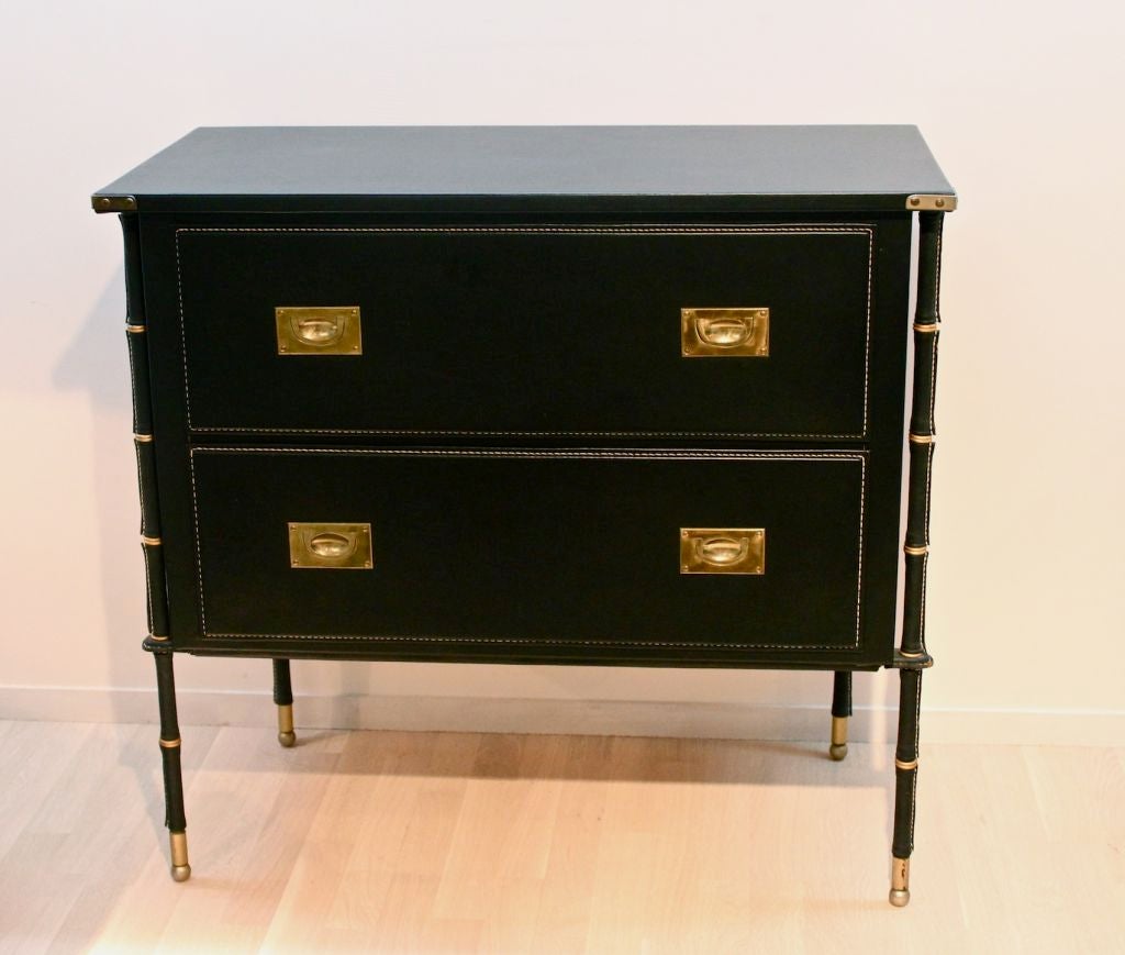 Two drawer chest covered in skai with faux bamboo legs. Stitched skai drawers with military style pull handles.