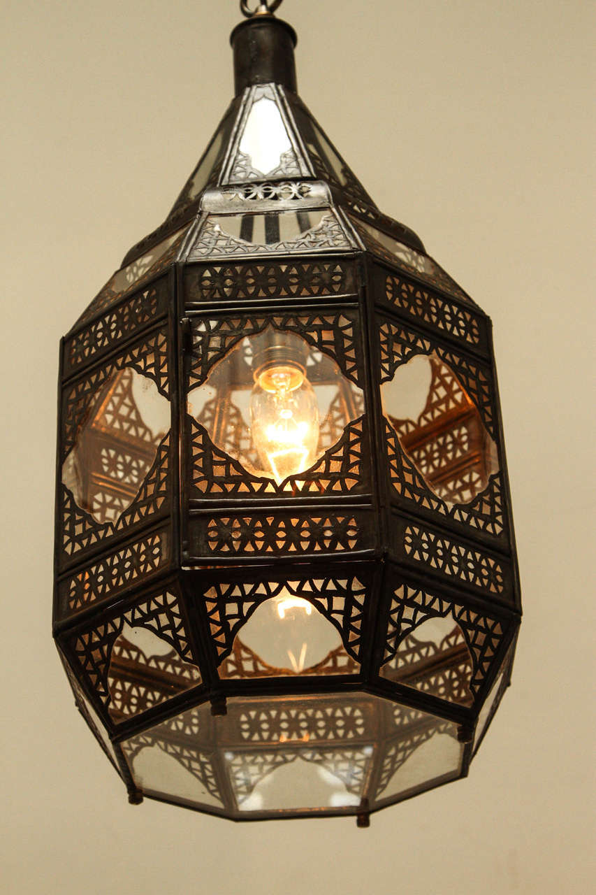 Moroccan Moorish clear glass lantern with intricate metal filigree. Octagonal shape, delicately handcrafted by artisans in Morocco. Bronze metal color finish. Could be used hanging from the ceiling or seating on a table, or as a wall sconce. Comes