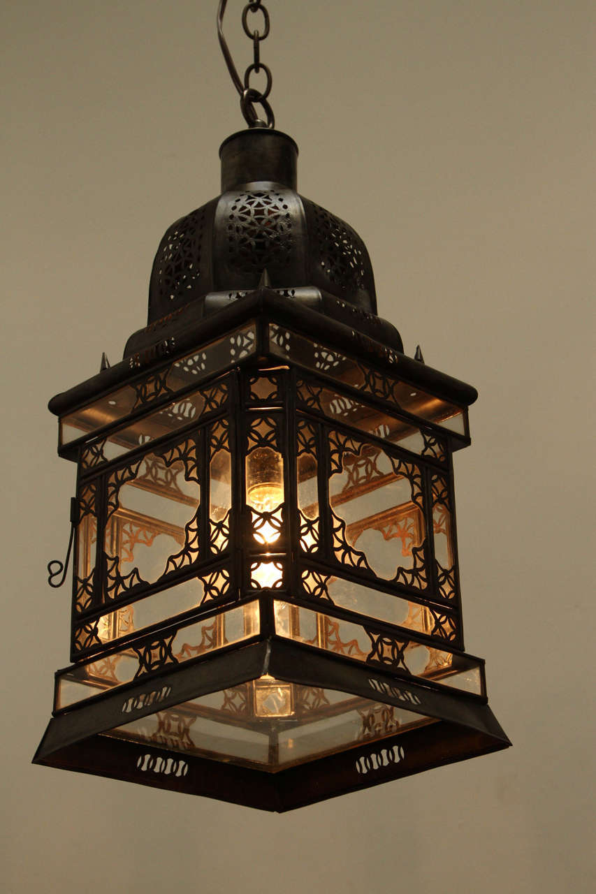 Moroccan hanging clear glass lantern with very nice intricate filigree metal work.
 Handcrafted in Marrakech Morocco by artisans.
 Wired with one light socket max light bulb: 60 watts. 
Comes with chains and ceiling canopy ready to hang.
Set of 4