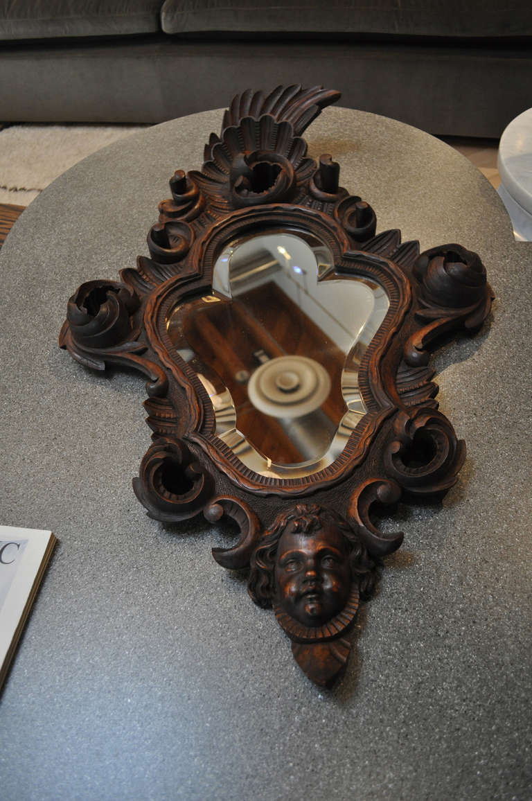 Exquisitely and ornately carved walnut mirror with cherub face detail.