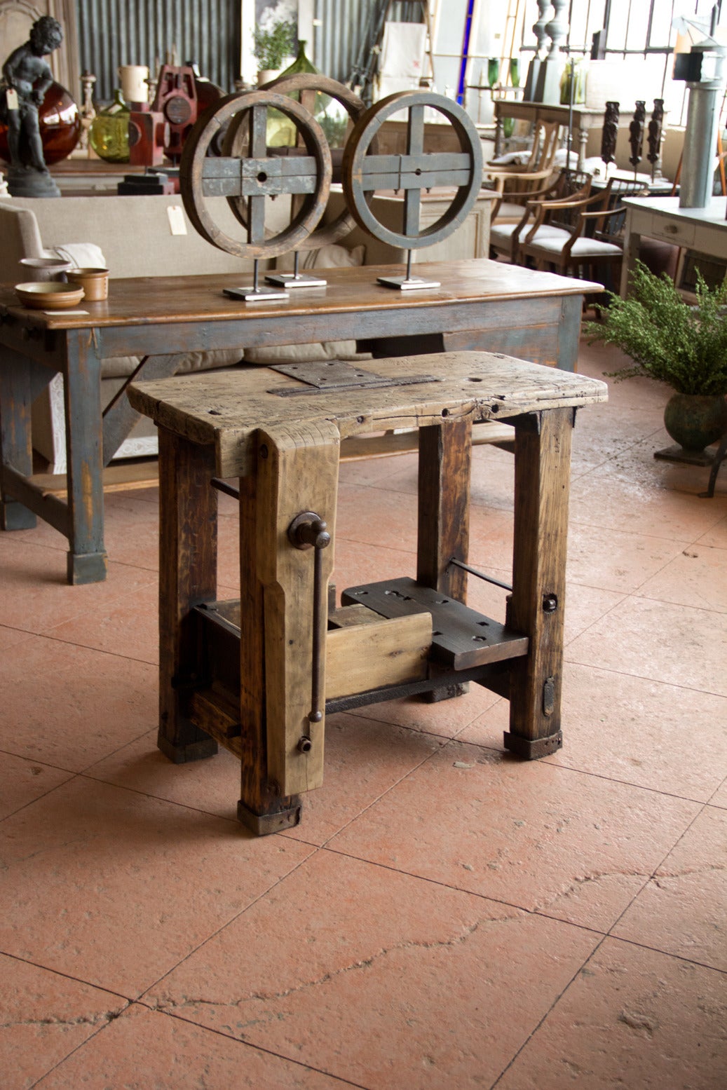 An unusual small French antique gnarly work bench full of character. The top has an unusual iron plate and it comes with its original vise and hopper.