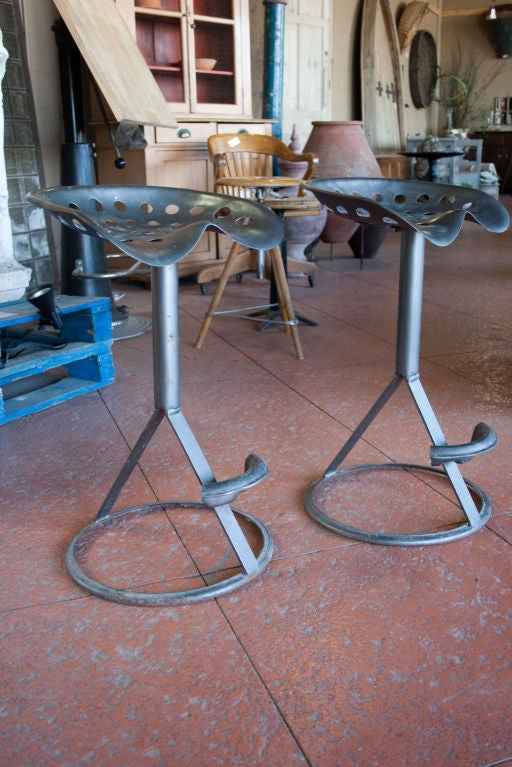 Funky pair of vintage tractor seats repurposed as bar stools. The foot rests have also been made from old tractor seats. They have a good industrial shape and feel.