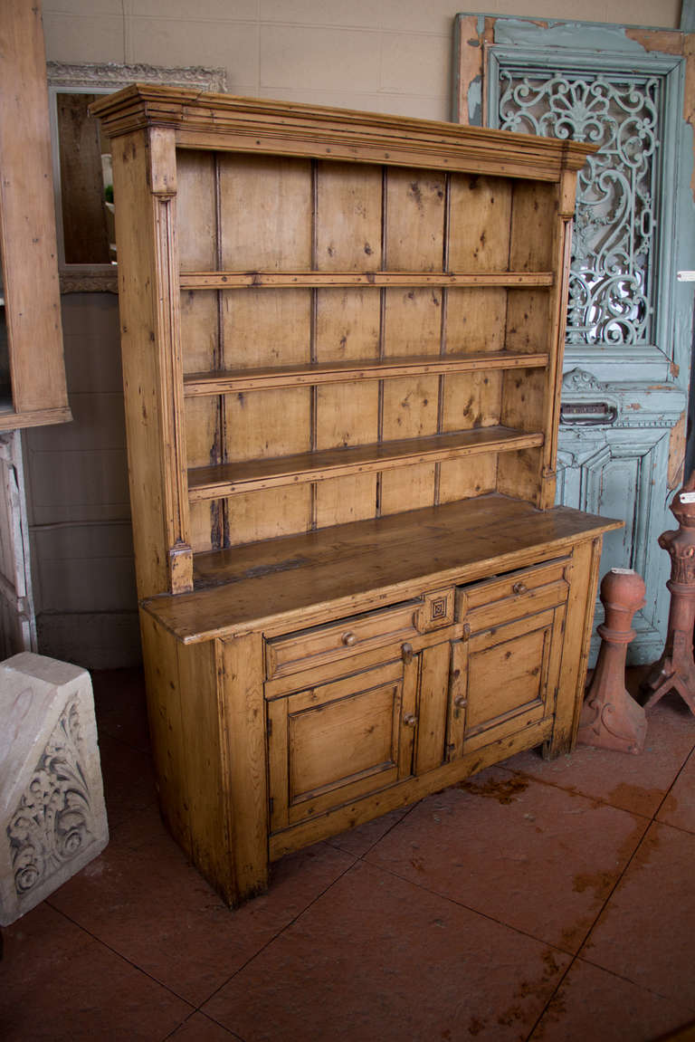 A really wonderful mid 19th century one piece pine County Cavan Irish dresser for your Downton Abbey inspired kitchen.  It has two drawers and 2 cupboards with its original brass hardware.  The plate rack is backed with original pine planking. 