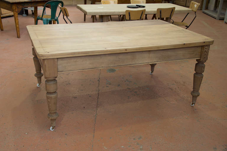 Wonderful antique English pine scrub down table with turned legs .  The underneath has been reinforced to give it extra stability and casters added so that it can be moved around. Would work well in both a residential and a commercial space.