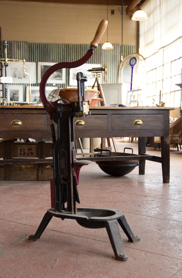 Antique French cast iron wine bottle corking machine with remnants of its original red paint.