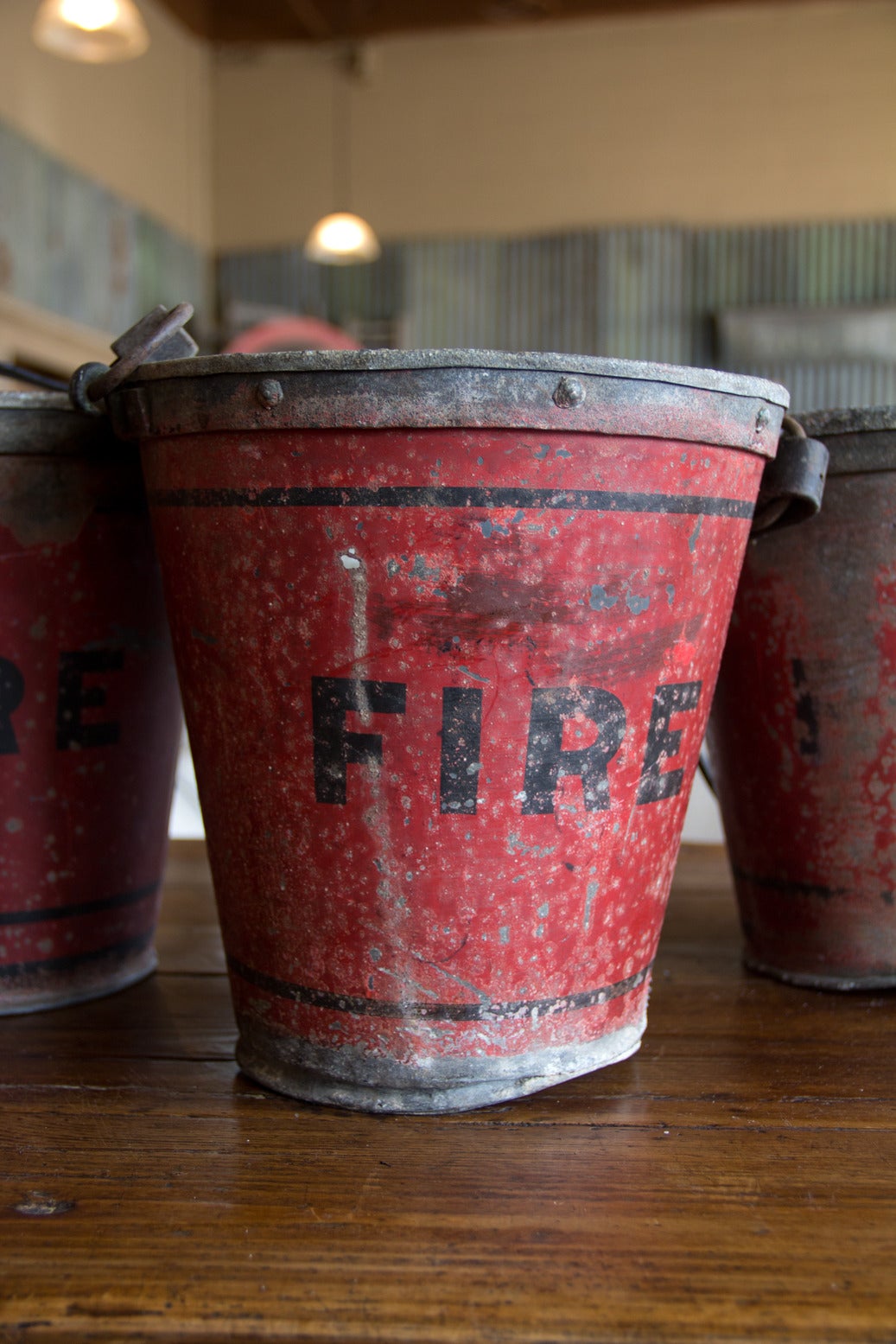 Wonderful set of two English painted metal fire buckets. We originally had 3, but have since sold one, remaining two sold as set. The tops are riveted and each one has a leather handle. Painted red with black 