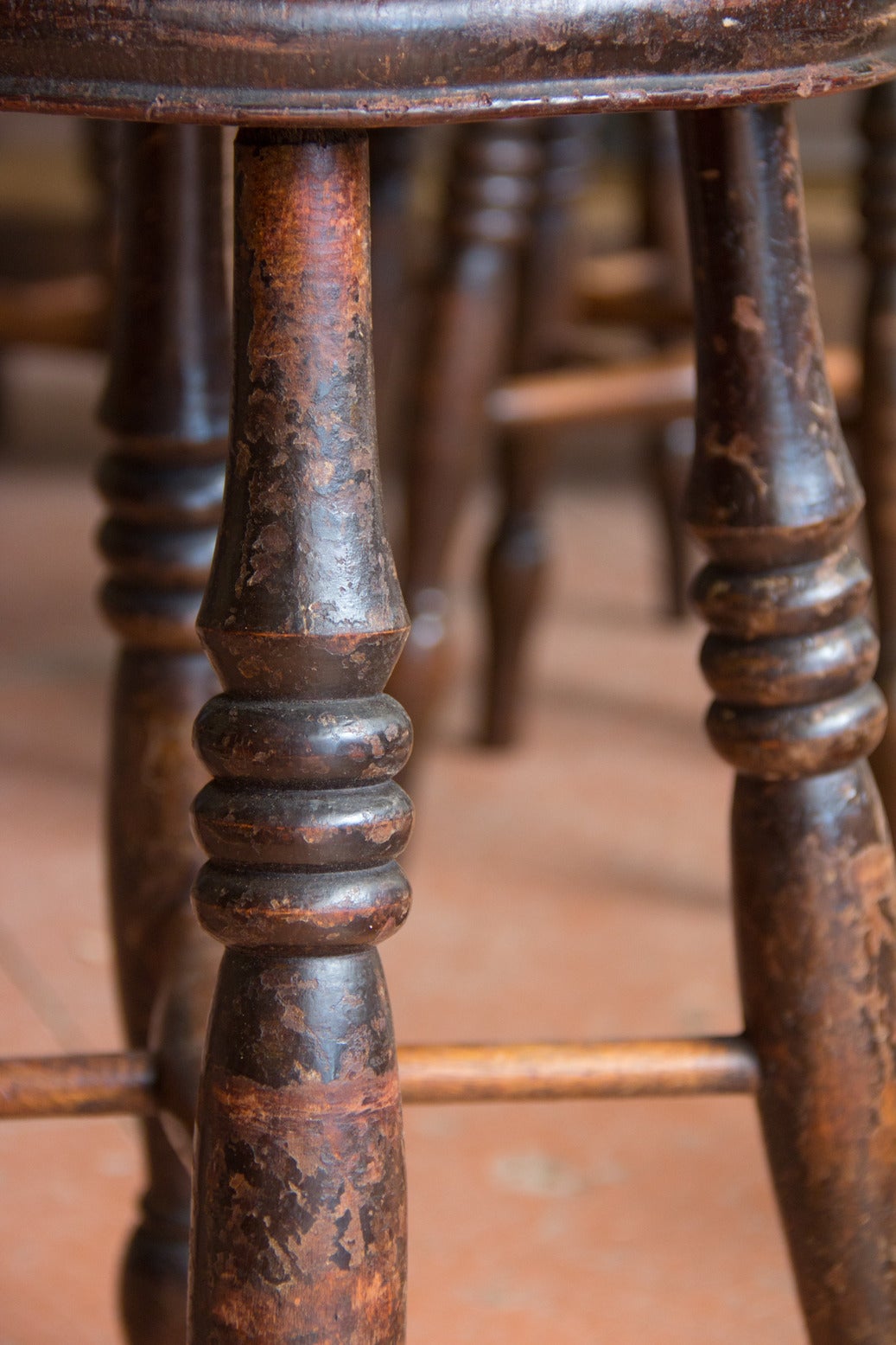 Set of four antique English elm pub stools with cross stretcher and beautiful turned legs.