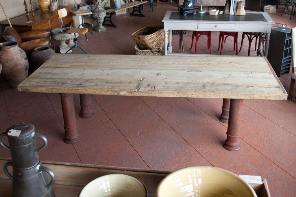 This huge 10 seater dining room table was made in France in the 21st century by repurposing  19th century salvaged wood for the top and original Victorian cast iron bollards for the legs.  The original terra cotta paint colour is still evident on