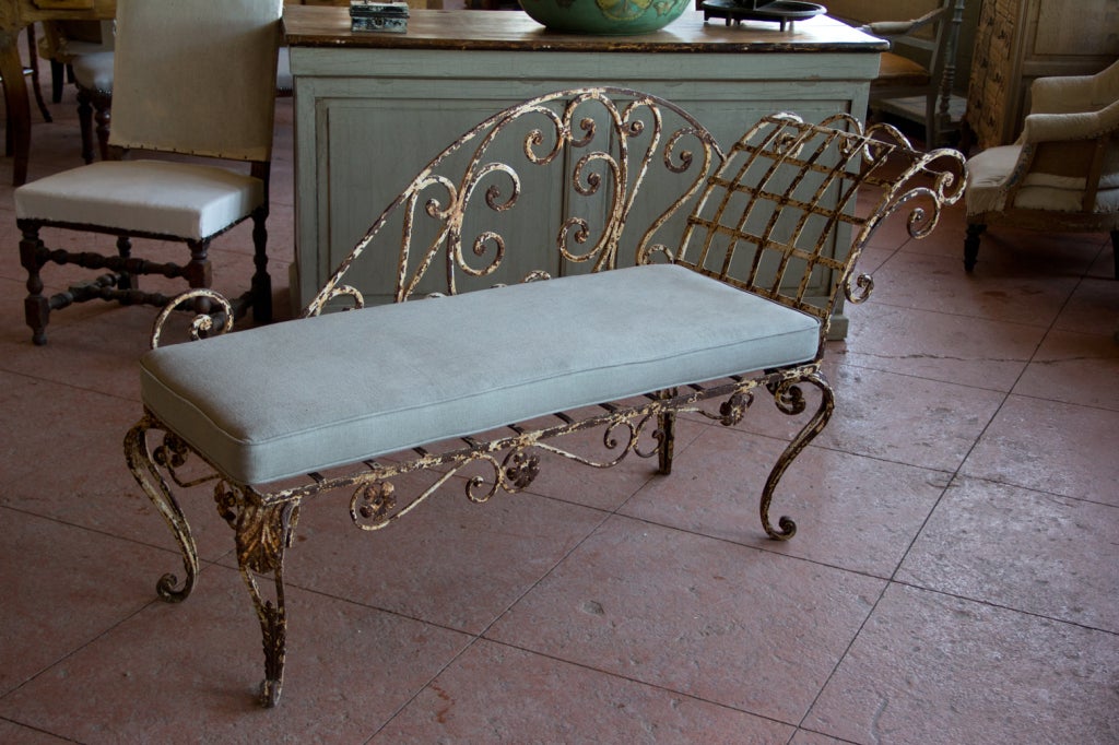 Beautiful antique wrought iron English chaise with its original paint.  It has a newly upholstered cushion in Belgium linen.  The chaise was recovered from a disused orangery in Bushy Heath, Hertfordshire, UK