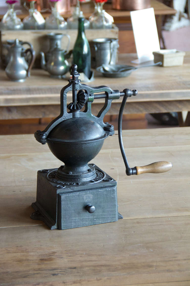 A much sought after, circa 1900 antique French cast iron table top coffee mill (moulin a cafe) made by Peugeot Freres. It has a wooden drawer and handle with traces of its original green paint.