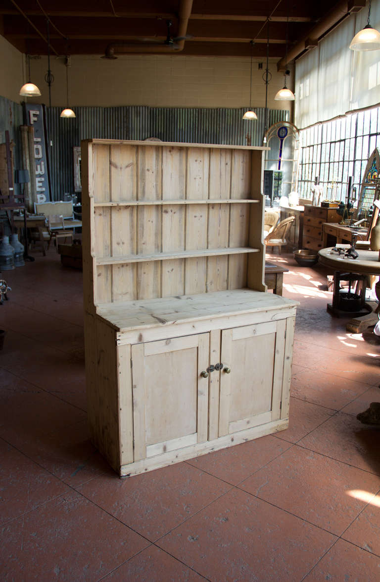 This rustic pine Victorian one piece Irish farmhouse dresser is a great size that would fit most kitchens.  It retains its originals brass knobs and latches. At some point it was stripped and no wax or paint applied.  It looks lovely as is, or you