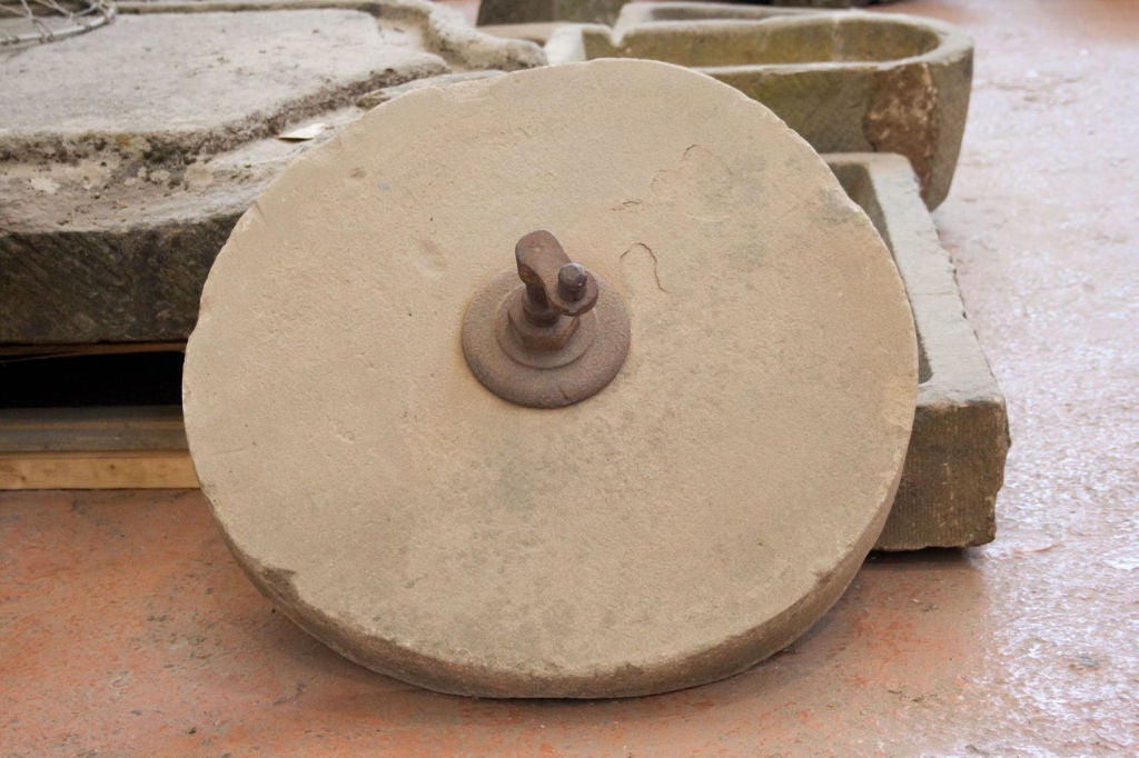 Very old stone grinding wheel that still has its iron handle.  A great garden piece.