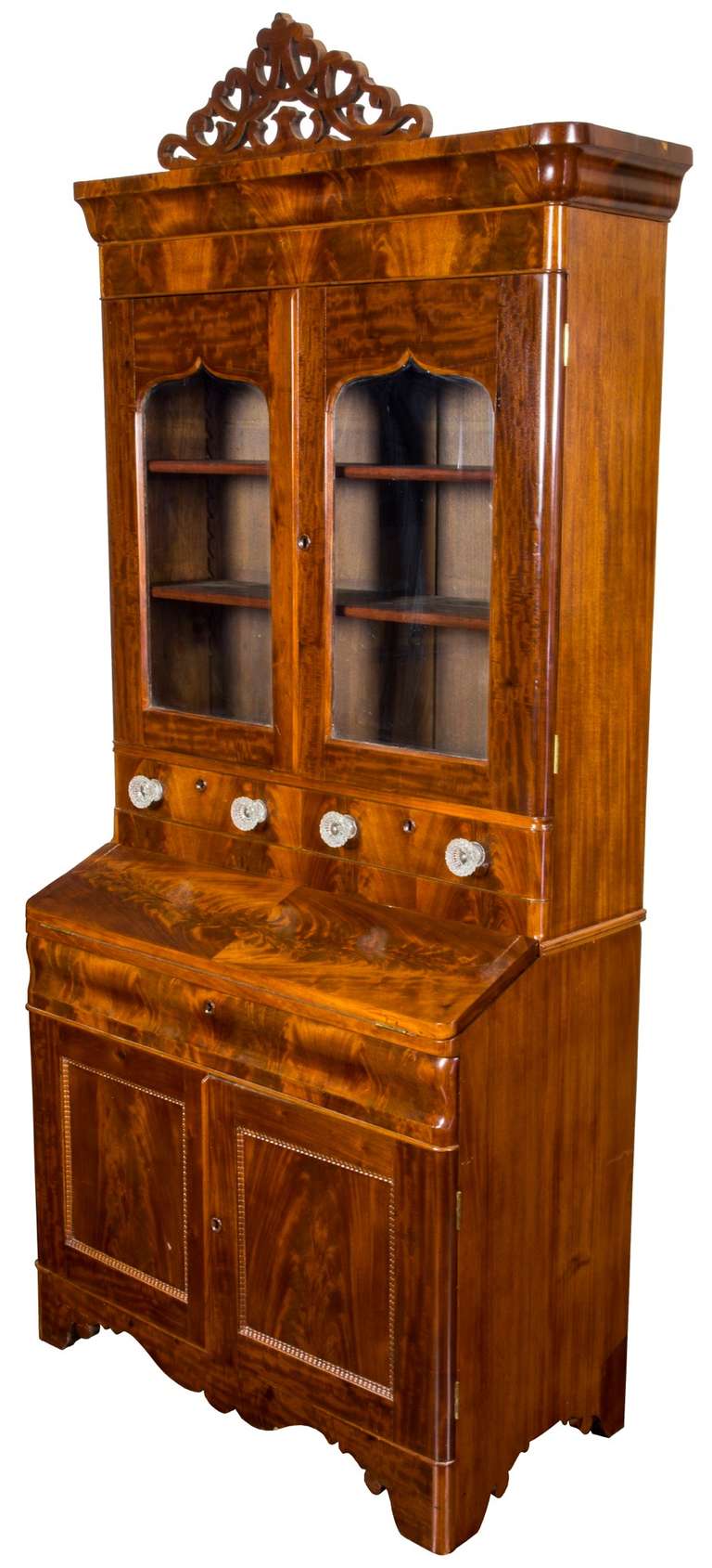 This secretary employs Classic Gothic arches in its upper doors, which are generally in-filled from behind with either fabric or left open as a bookcase, given the full shelving. The upper pediment retains its original open scrolled fretwork above a