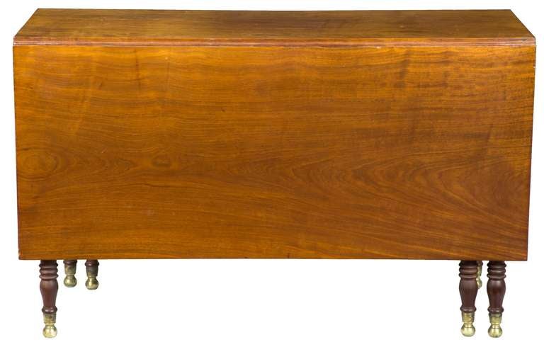 This table exhibits a dense single board mahogany top and leaves of large size in excellent condition. There are six classically turned Sheraton legs which terminate with brass ball embellishments, typical of this period. While these tables were
