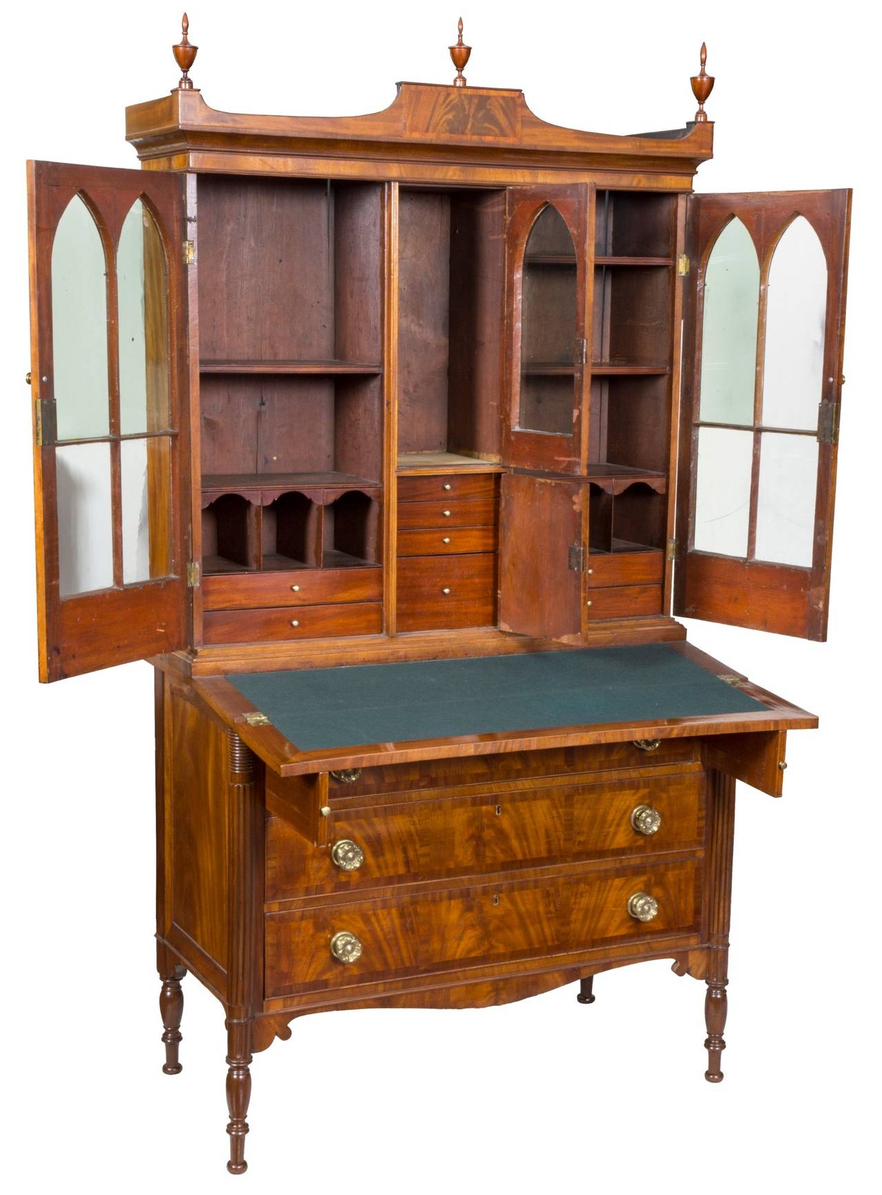 This secretaire has Gothic arch doors with an interesting central glass door above a prospect door opening to four drawers. This is quite rare, and offers the benefit of the full interior often found in slant lids desks, plus a bookcase above, all