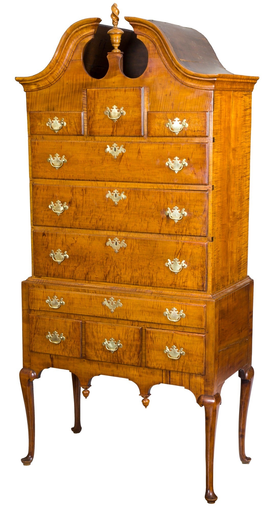 This highboy is of a small-scale with a width of only 35 in. and has a very delicate, fine appearance, with a beautifully formed pediment, which flanks its original urn and finial. While this form exists, finding one in tiger maple with a glorious