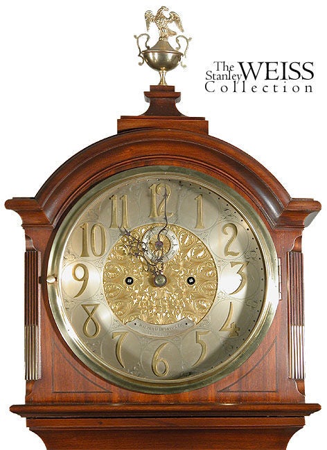 This clock is a rather short tall case clock and is stylized on English models with the bonnet of the upper case being closely circumscribed along the round brass bezel which is further echoed by the round dome-shaped glass of the side lights that