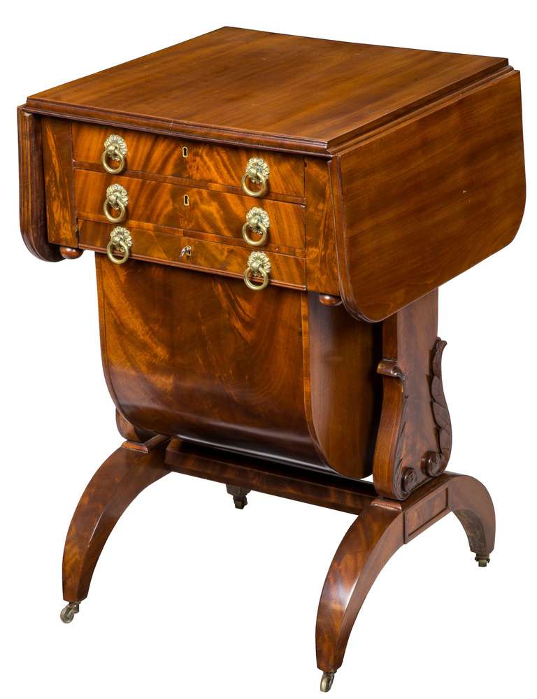 The top of this worktable has two drop leaves composed of solid mahogany with molded edges and above three drawers, the top which has a writing desk, the middle drawer has small dividers and the bottom drawer, a sewing basket, (which often is lost)