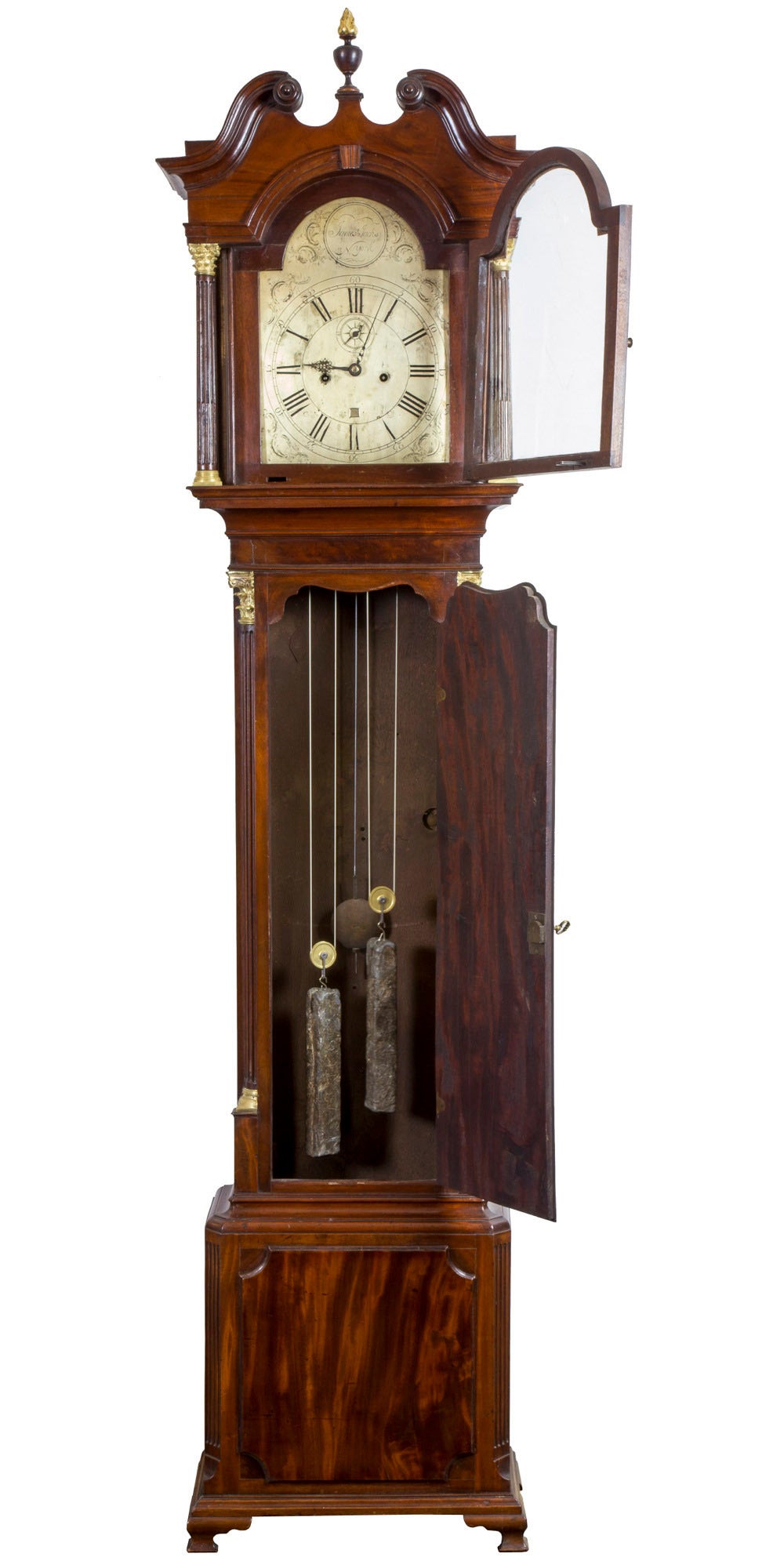 This tall clock is composed of solid, dense ribbon grain mahogany, circa 1780. The panel door and base panel are truly dramatic and bring a vitality to this clock which is supported visually by fluted corner moldings with capitals that are the