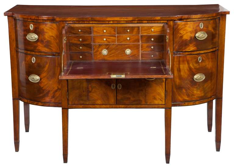 This sideboard retains a golden mellow tone, which has over time enhanced the strongly figured mahogany used throughout; all is embellished in a restrained manner with defining ebony edging including a central oval. The butler's desk is as fully