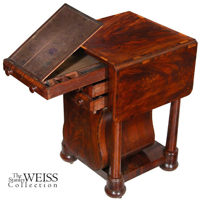 This worktable has an unusual lyre form basket composed of highly figured mahogany, crossbanded with rosewood. The crossbanding element is carried through throughout on the plinth at the base, the drawer edges and on the top, including its leaves.