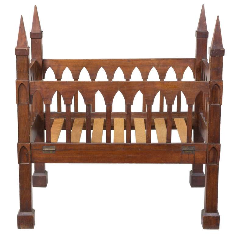 A rare Gothic crib, black walnut, United States, circa 1835-1845. This crib personifies the Gothic idiom with its multitude of Gothic arches and pedimented post supports, which create a formidable and dramatic statement.

This unusual form was