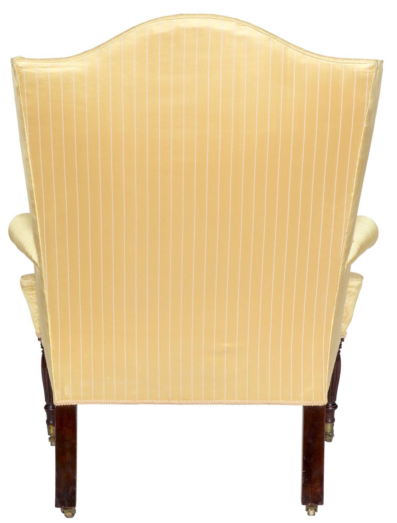This wing chair retains the wing chair form, as seen in the last half of the 18th century with the exception of reeded legs, which harken to the classical period. The legs are beautifully turned and reeded and retain their ample-sized wheels both in
