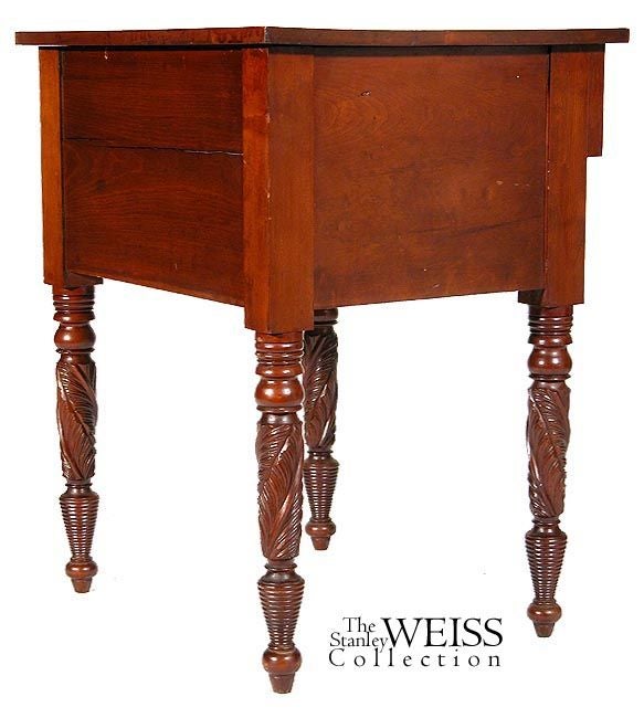 This two-drawer stand makes a bold statement with a smorgasbord of wood types and extremely fine carving. Stylistically, this formidable piece is slenderized by the use of the stepped back lower drawer and the multifaceted upper drawer.

The top