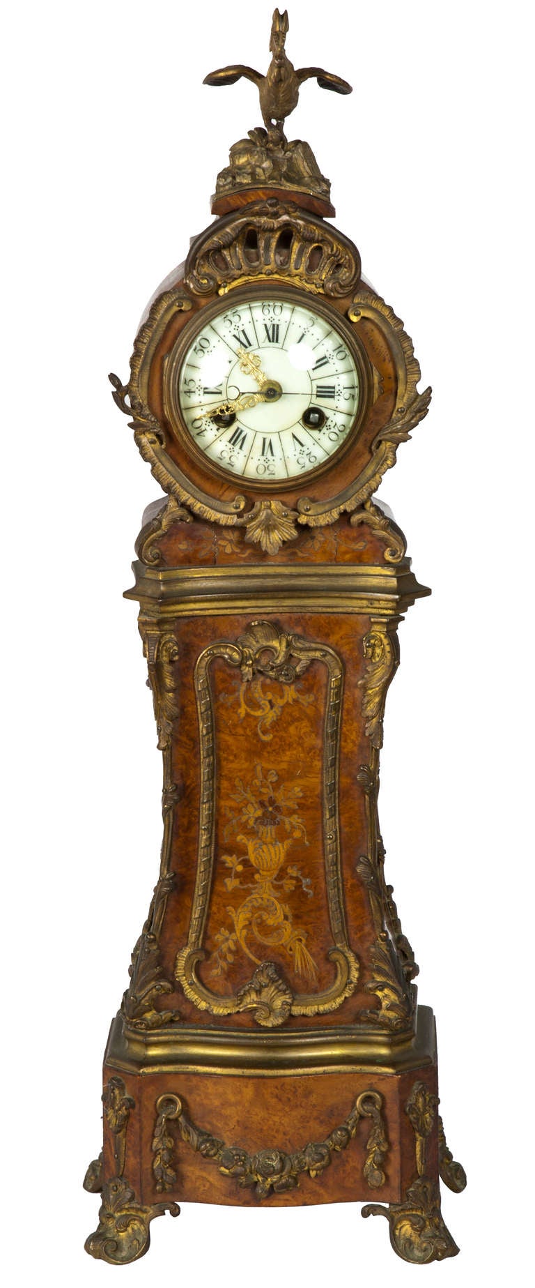 This small clock, composed of burl walnut is further embellished with fine wood inlay and gilt mounts. The shaping of this clock is French and every surface seems to curve and is integrated in the form of a larger tall case clock. Many of these