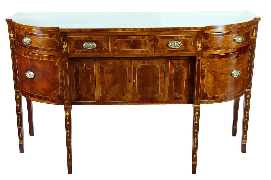 This is an exceptional sideboard in pristine condition. It is fully developed with bottle drawers flanked by convex side drawers, all surrounding small inlaid doors. This model relates very closely to a sideboard handled by Wayne Pratt, Inc. of